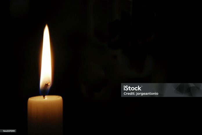 White candle burning in the dark