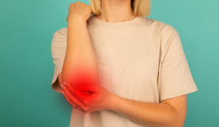 Young,Woman,Experiencing,Pain,In,Elbow,Jointon,Blue,Background.